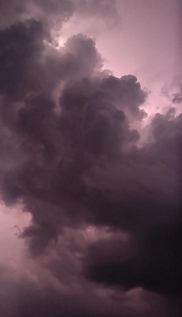 Picture of a cloudy sky colored pinkish color from the lightning.