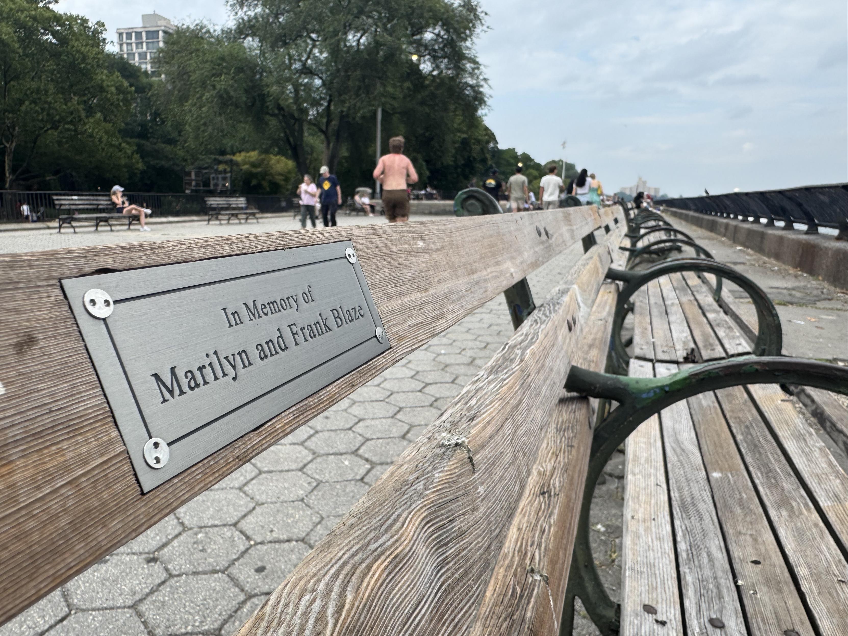 A park bench with a placard reading “in memory of Marilyn and Frank Blaze”