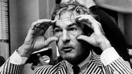 Timothy Leary in a striped suit making / owl shapes with his hands around his eyes. I assume he’s coming out of one of his many legal situations.