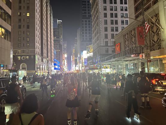 Photo of many skaters rolling down Seventh Ave towards Times Square after dark, shot from amongst them.