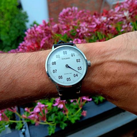 A one handed decimal watch showing the time as just past 3:50.