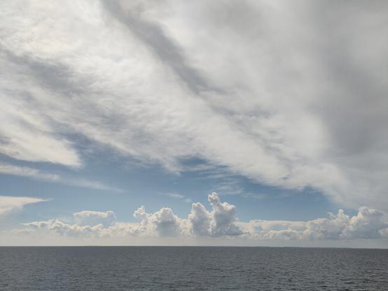 Piles of white coulds reaching into the sky from the sea