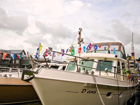 Another white ship. It is called ‘D'ans’. This ship also has strings with colourful pennants hanging from them. This time, they are not national flags, but event pennants. Cloudy sky, but no rain.