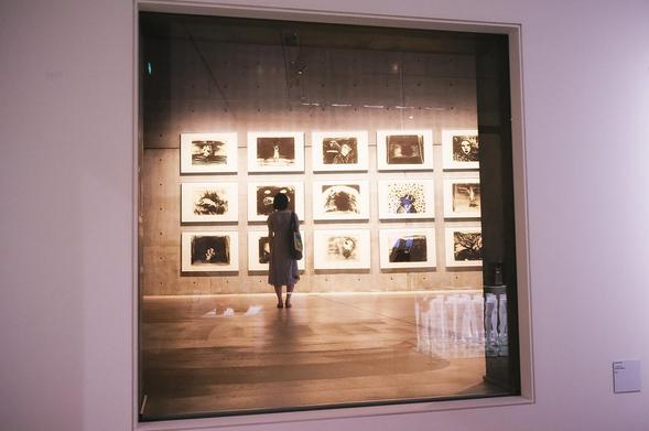 A woman seen through a door window viewing art prints at an art gallery in Tokyo