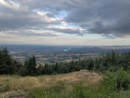 Panorama sur la vallée du Rhône pris depuis le Mont Ministre dans le Massif du Pilat. Au centre, on voit le fleuve couler vers le Sud. A l'horizon, les Alpes sont très pâles presque fondu dans le ciel partiellement nuageux.
