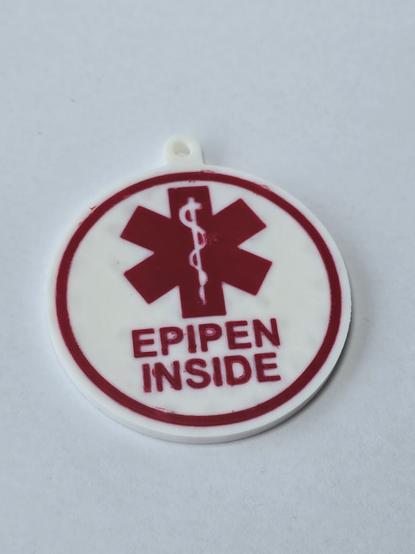 a 3d printed white & round sign, with red lettering and symbol showing the words "epipen inside" and a medical icon