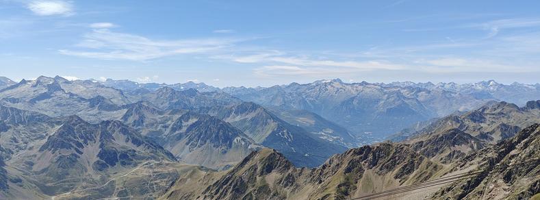 Photo du panorama depuis le Pic du Midi. Des sommets de montagne gris-marron sois un ciel bleu avec quelques nuages fins.