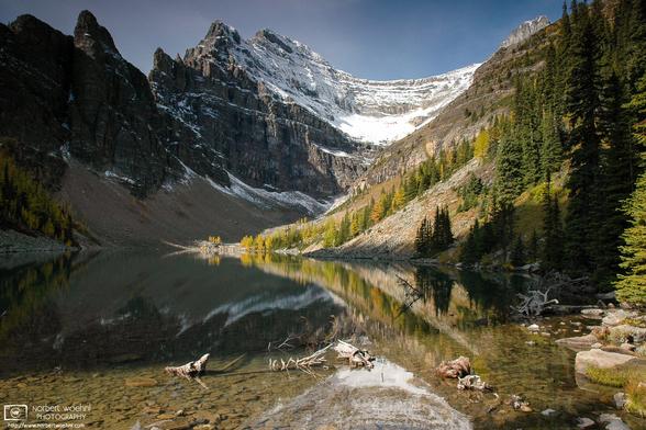 Lake Agnes in Banff National Park, Alberta, Canada, as seen from a spot near the Lake Agnes teahouse. Some of the trees in the background are displaying autumnal colors.