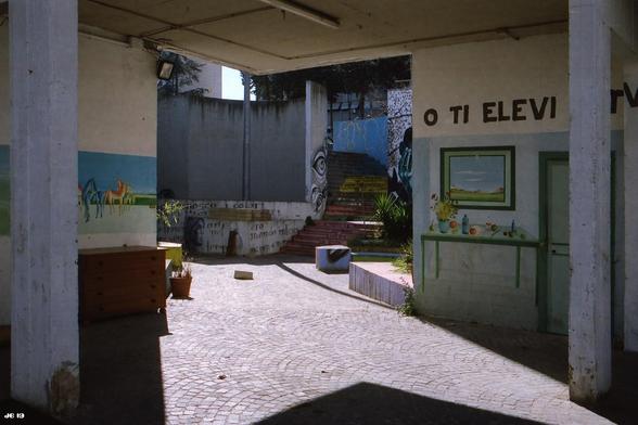 Farbfoto mit Blick in einen Hinterhof des gigantischen Corviale-Wohnkomplexes in Rom, Italien, im Baustil des Brutalismus, verschönert durch etliche naiv ausgeführte Wandgemälde. Leica R4 mit 50 mm Summilux auf Kodak Portra 160.