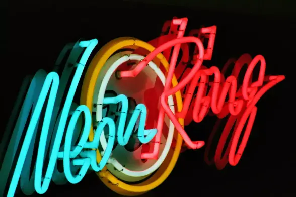Neonreklame mit dem Text "Neon Ring". Neon ist in türkis, Ring in Rot, in der Mitte ein oranger und ein weißer Kreis.