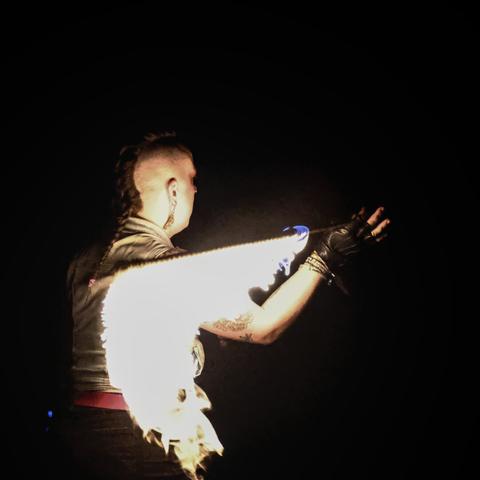 The same person as in photo #1, seen from behind, her sword horizontally behind her (toward the camera) as she spins it.