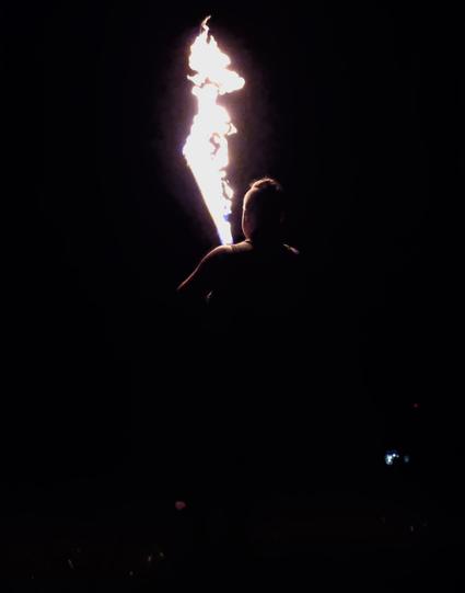 The same person from photos #1 and #2, seen from behind. In this photo there is only the outline of a head/torso (with mohawk), illuminated by a partially occluded flaming sword. Everything else is black.