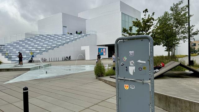 Sticker on the back of a road sign representing a cartoonish hand linked to foot by a black limb and is ticking the foot with a feather. The text on the sticker says «  The Vicious Cycle » by NoeGrit