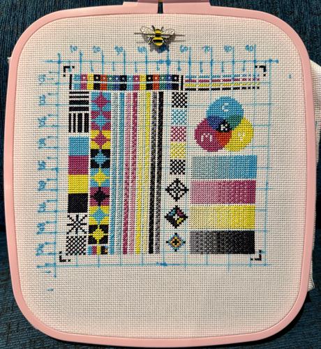 A cross stitch of a printer test page, with blocks of cyan, magenta, yellow, and black in various combinations. In the top right there’s an overlapping area where the colours also combine to make red, blue, and yellow.