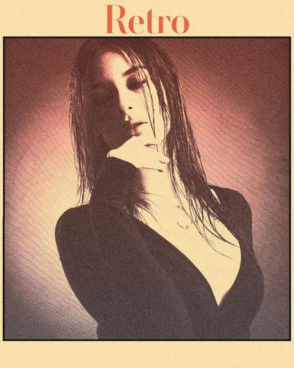 A woman with wet hair poses with a hand under her chin, looking down. She wears a low-cut black top. The image has a sepia-toned, vintage effect with a grainy texture, bordered by a thick black line. The word "Retro" in bold orange font is at the top against a pale background.