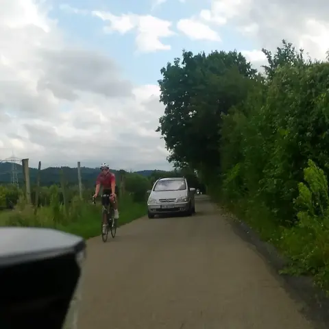 Mir kommt auf dem Wirtschaftsweg ein silberner PKW entgegen.