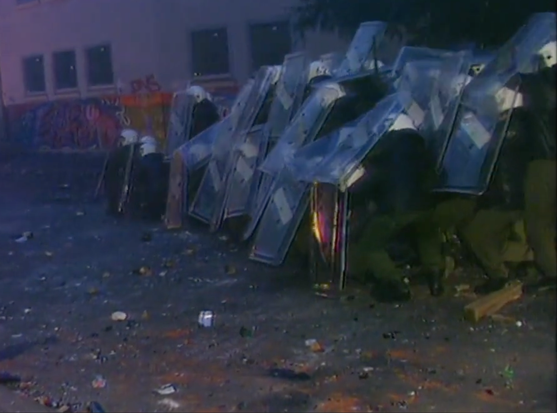 Bullen in der sogenannten "Schildkrötenformation" werden mit Flaschen und Steinen von oben versorgt. Bild aus einer tagesschau-Sendung vom 6. August 1995.
