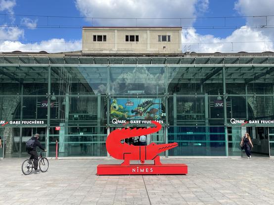 This picture shows the back entrance of the Nîmes train station, in southern France. In the middle of the photo, there is a sculpture of a red crocodile, the animal being the city's symbol.