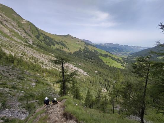 Two climbers on the via ferrata with the valley below them