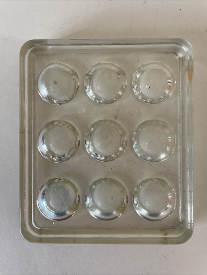 A small glass rectangle with 9 hemispherical depressions in a 3 by 3 grid.