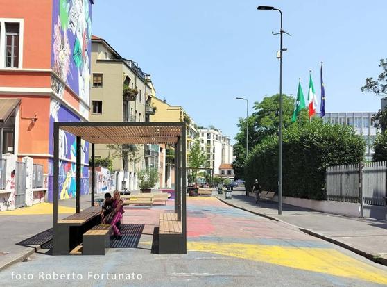 Una struttura ombreggiante formata da una tettoia sotto cui sono posizionate due panchine.

La struttura è nel mezzo di una strada asfaltata, in pieno sole