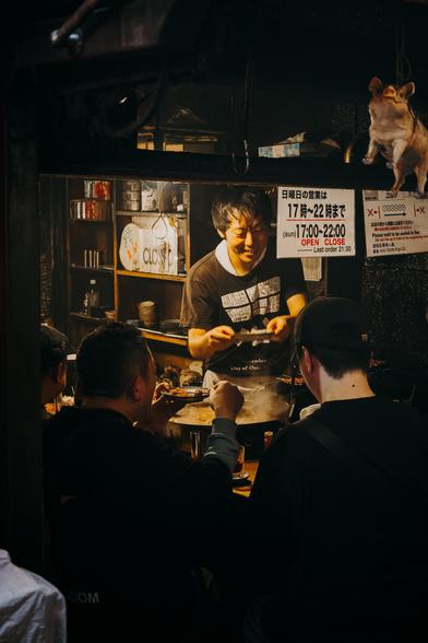 photo of a chef reaching food to a customer in a very small japanese restaurant