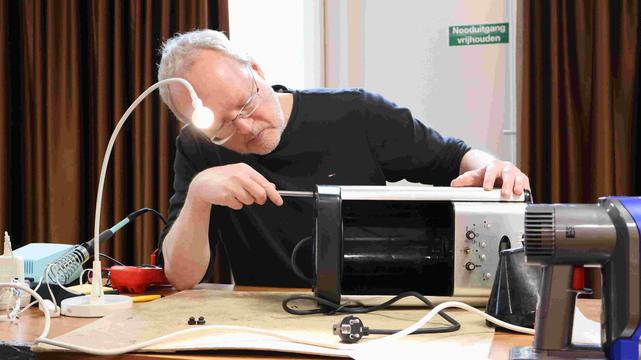 Ton onderzoekt een lekkende koffiemachine in het Repair Café De Meent Amstelveen