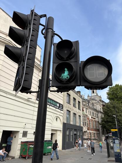 Traffic lights with street crossing sign showing green wheelchair user rather than typical ‘man walking’ sign.