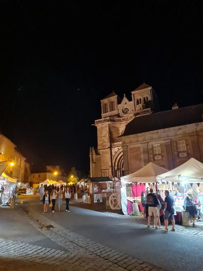 Église prieurale de Souvigny la nuit, entourée des stands de la foire médiévale.