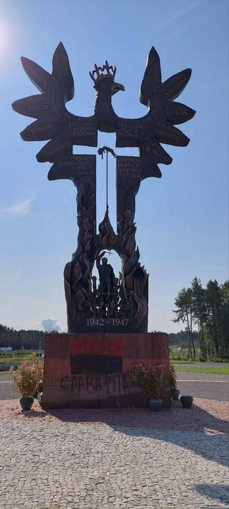 An eagle-like monument commemorating victims of Volhynia tragedy with an ugly graffiti at the bottom saying "Slava UPA" but in a incorrect alphabet, mixing Ukrainian and Latin letters