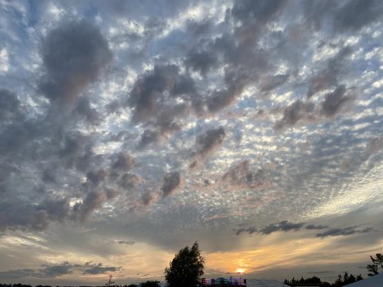 Sky with setting sun and different layers of clouds, with some RGB leds in the distance.