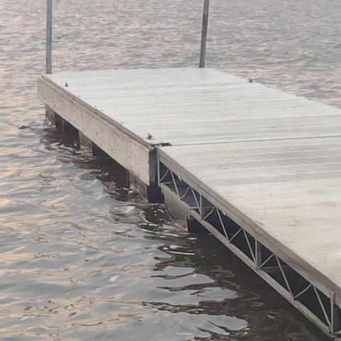 A wooden dock by a boat ramp in the Mississippi River. Early morning light on the ripples of water.