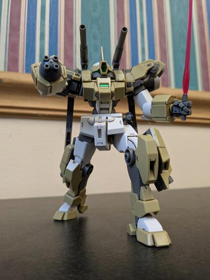 The HG Demi Barding aiming its shoulder cannons and multi cannon right hand above the viewer. It is holding a beam saber in its left hand.