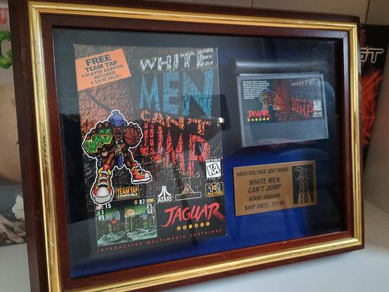 a photo of white men can't jump for the atari jaguar. the game is framed and features a commemorative sign to celebrate the game's release date.