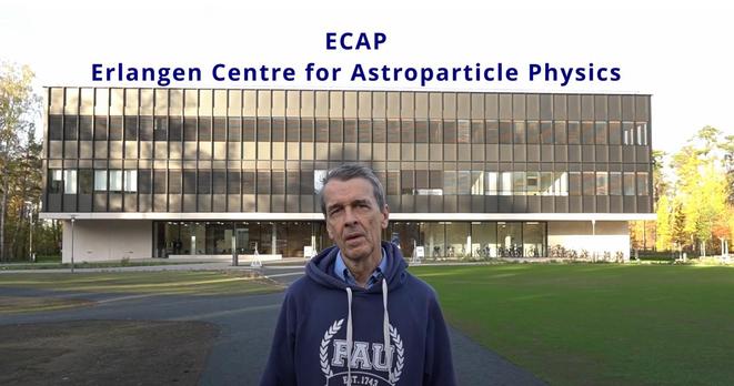 Screenshot des verlinkten Videos. Hinter mir ein modernes Gebäude. Beschriftung:
ECAP
Erlangen Center of Astroparticle Physics