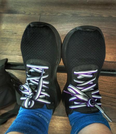 Ein paar Turnschuhe mit Schnürsenkeln in der Asexual Pride Flag Farbkombination.