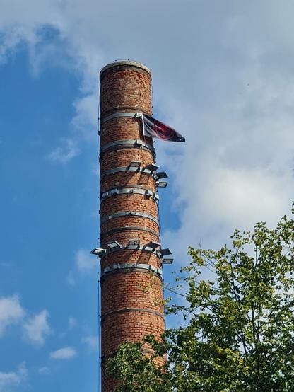 Komin a na jego szczycie czarna flaga z czerwonym pentagramem