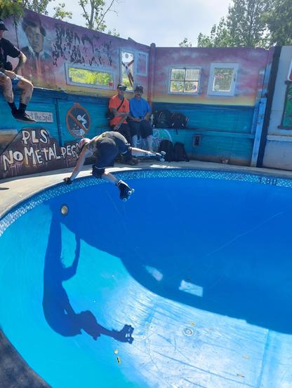 A rollerskater is doing a habdplant kickback in a blue pool