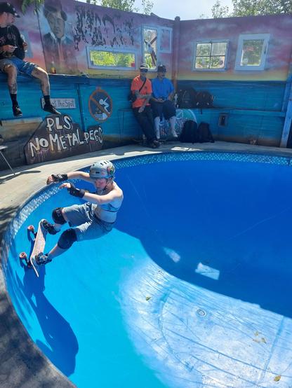 A surfskater riding in the deep end of a blue pool