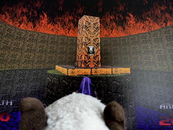 English: Screenshot from the game Doom 64. It shows a round recess in the level, the floor of which is covered with water textures, with a dark brown wall rising in a semicircle at its edges, the lower half of which is finished off with a narrow, dark gray textured ridge. In the center is a platform with a pillar on it, which is designed in a lighter brown color with decorations reminiscent of H.R. Giger, and a switch is embedded in it. The flames of hellfire can be seen as the sky—as my human puts it: very fitting for our present day.
In the foreground is the head of a stuffed cat, photographed in such a way that it looks as if the cat is playing the game.

Deutsch: Bildschirmaufnahme aus dem Spiel Doom 64. Zu sehen ist eine runde Ausbuchtung im Level, deren Boden von Wassertexturen bedeckt ist, an dessen Rändern sich im Halbkreis eine dunkelbraune Wand erhebt, die in der unteren Hälfte noch von einem schmalen und dunkelgrau texturierten Grat abgeschlossen wird. In der Mitte ist eine Plattform, auf der ein Pfeiler steht, der in hellerem braun und mit an H.R. Giger erinnernde Verzierungen gestaltet ist, ist ein Schalter eingelassen. Als Himmel sind die Flammen des Höllenfeuers zu sehen - sehr passend zu unserer heutigen Zeit, meint der Mensch.
Im Vordergrund ist ein der Kopf einer Stoffkatze zu sehen, so fotografiert, dass es aussieht, als spiele die Katze das Spiel.