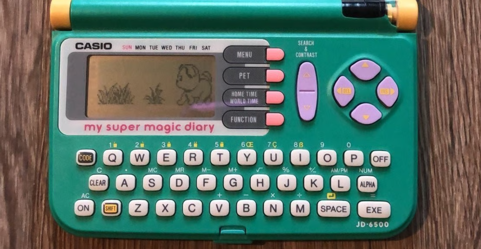 The bottom half of a Casio "my super magical diary" PDA, with green plastic, yellow hinges, a pink and purple buttons.
