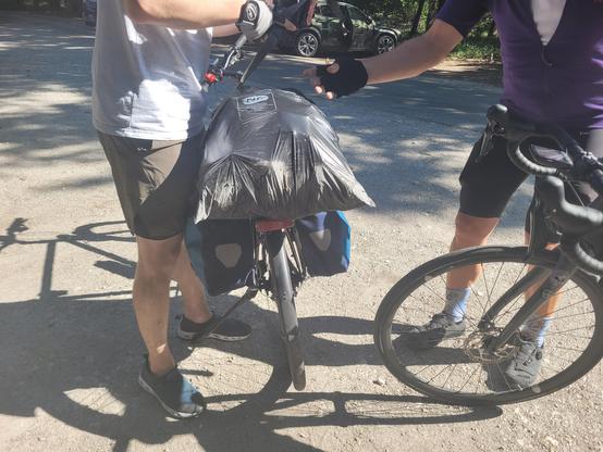 Deux cyclistes en train de fixer une poubelle à un porte-bagages
