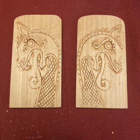A matched pair of plaques carved with Viking style dragon heads.