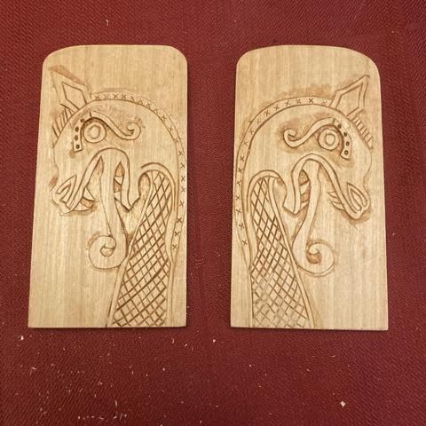 A matched pair of plaques carved with Viking style dragon heads.