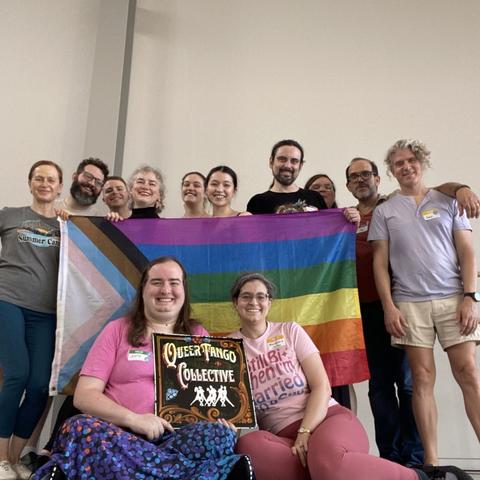 10 people stand behind a progress pride flag, and 2 sit with a "queer tango collective" sign