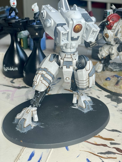 Front view of t’au riptide battlesuit in process of being built and painted. Legs are fully painted, but the torso only has base paints and now arms or head has been attached.