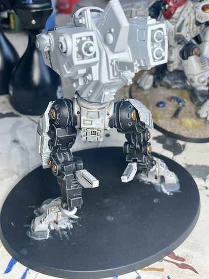 Rear view of t’au riptide battlesuit in process of being built and painted. Legs are fully painted, but the torso only has base paints and now arms or head has been attached.