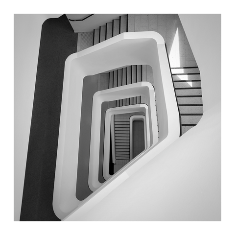A black and white photo of a staircase. Several levels are visible, but no person.