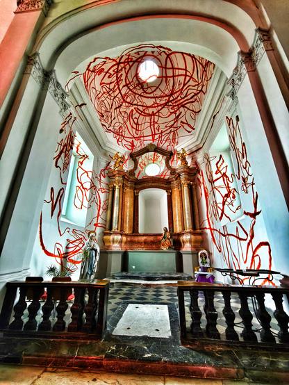 Auf die Wände einer Nische in einer Kirche sind rote Krakellinien gemalt.
