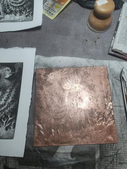Photo, plaque de cuivre gravée posée à côté d'outils et de tirages, sur une feuille de papier journal